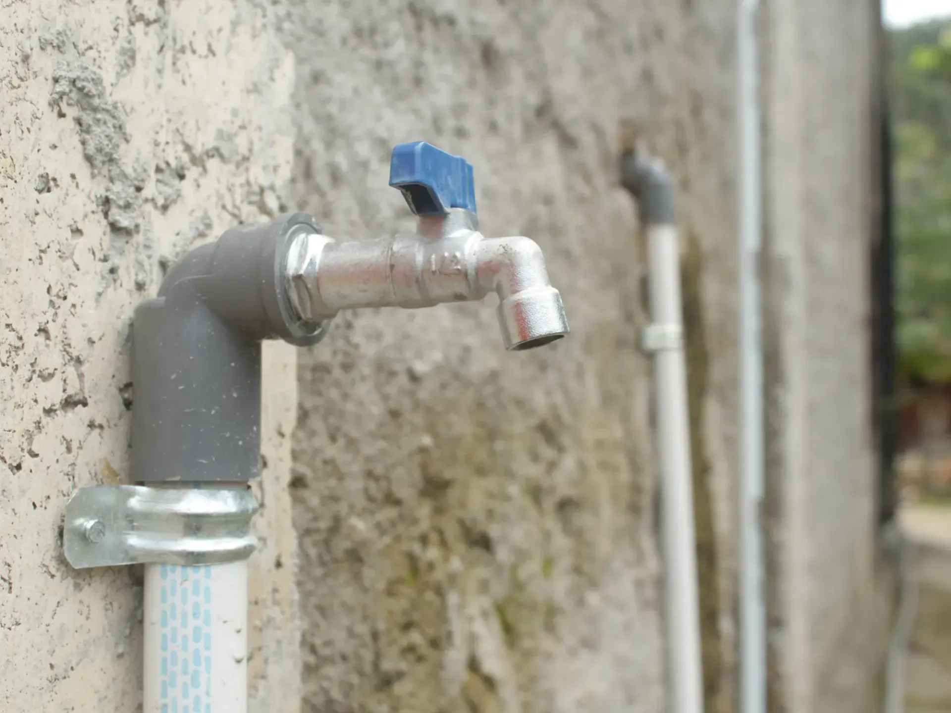 A faucet with a blue handle is attached to a wall in Southeast Portland