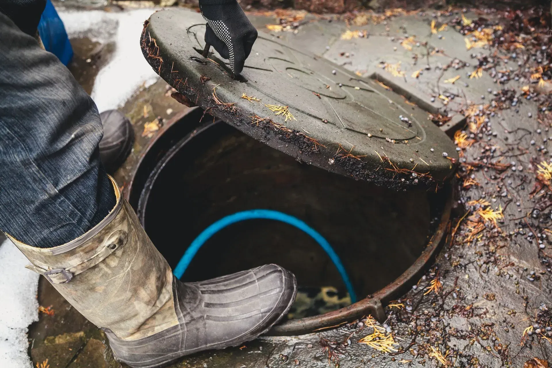 A person is standing in a manhole cover with a blue hose coming out of it in Southeast Portland