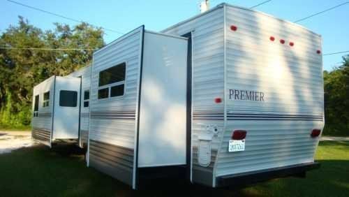 A white trailer with the word premier on the side is parked in a grassy field.