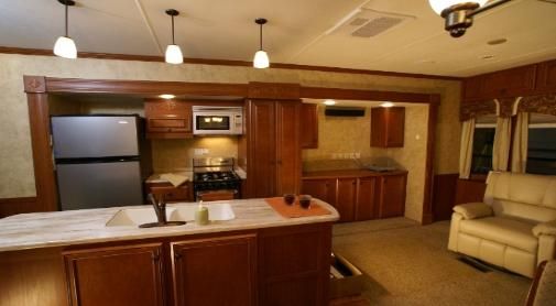 A kitchen with a refrigerator , sink , stove and microwave.