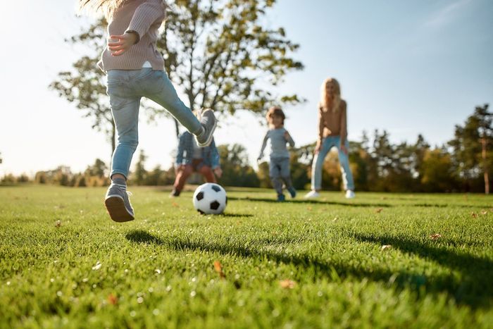 A group of children are playing soccer in a park.