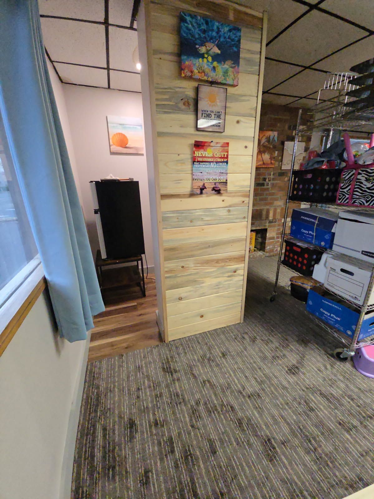 Modern office space with desks, computers, and black chairs. Wooden accents and large windows.