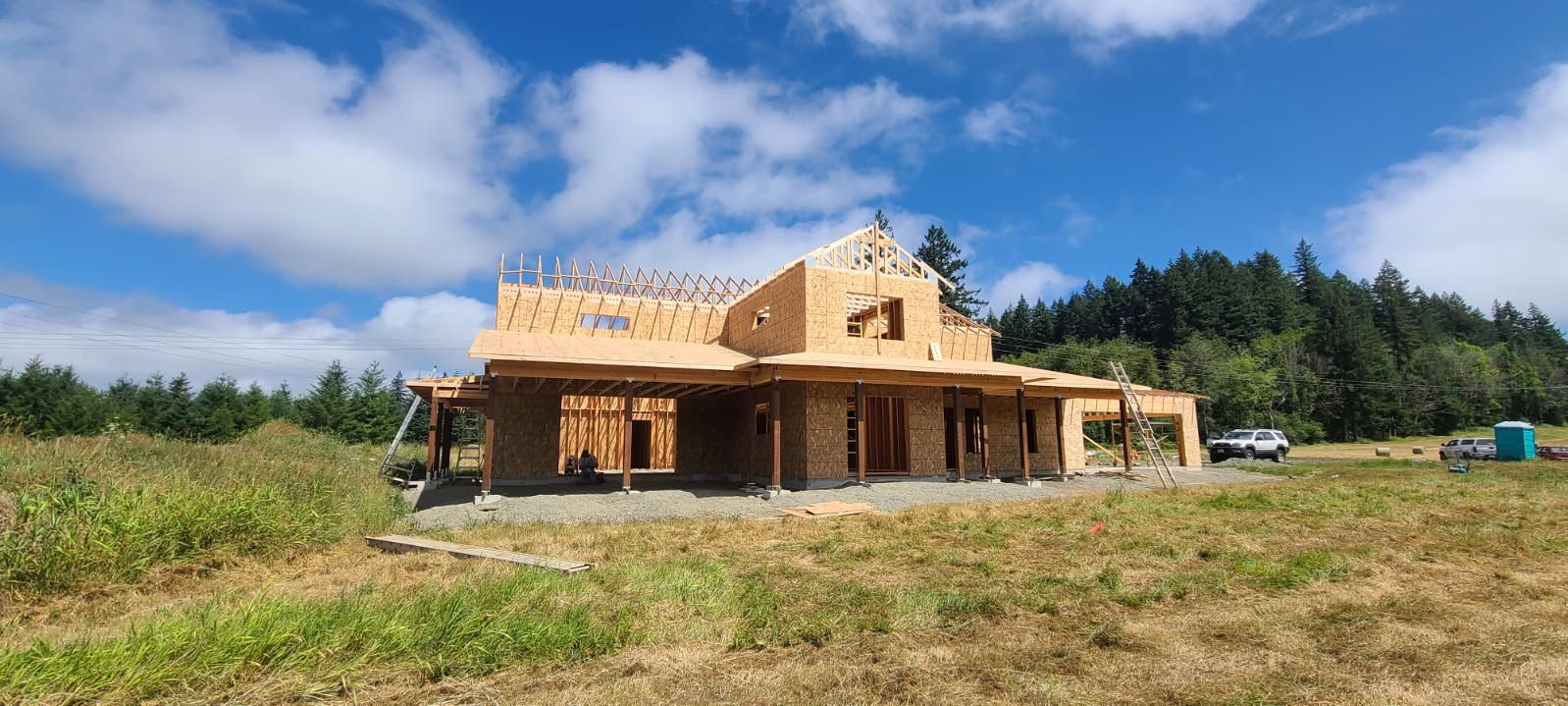 Wooden frame of a house under construction against a blue sky with clouds.