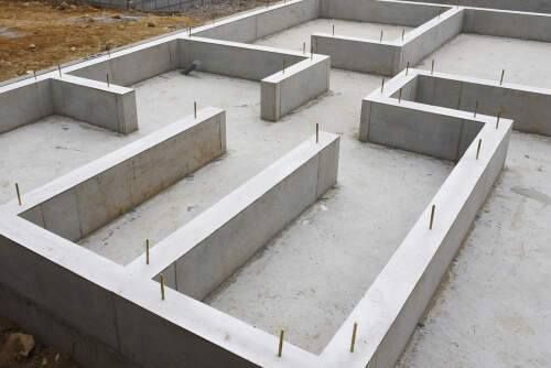 Concrete foundation of a building under construction, with protruding metal rods.