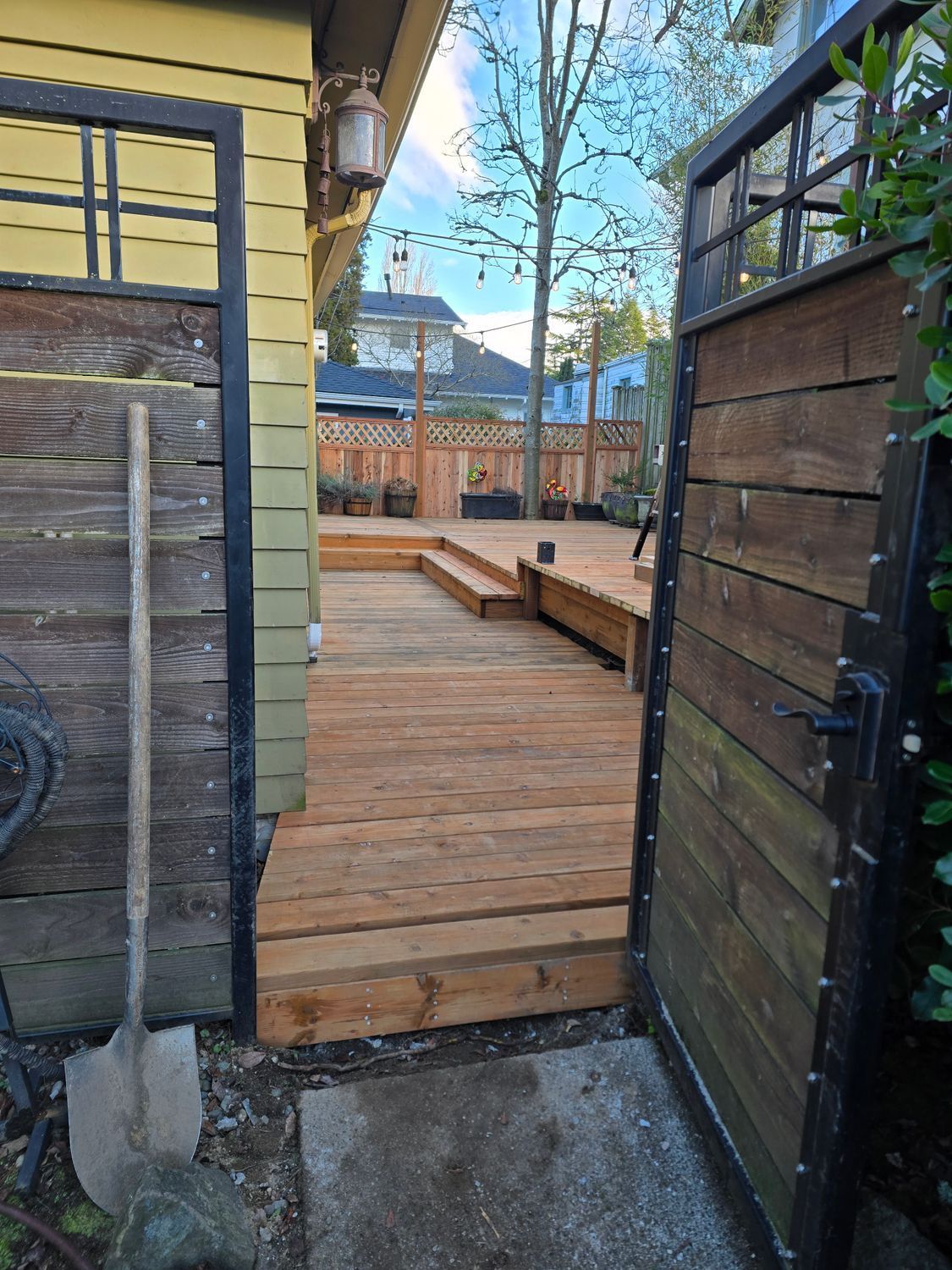 Wooden deck and gate with shovel leaning on a weathered building.