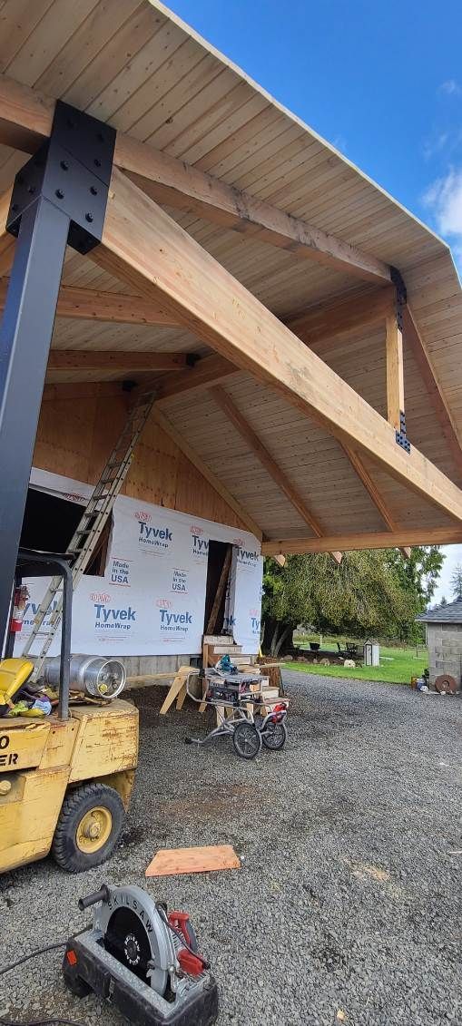 House under construction: wooden frame with window and door openings against a clear blue sky.