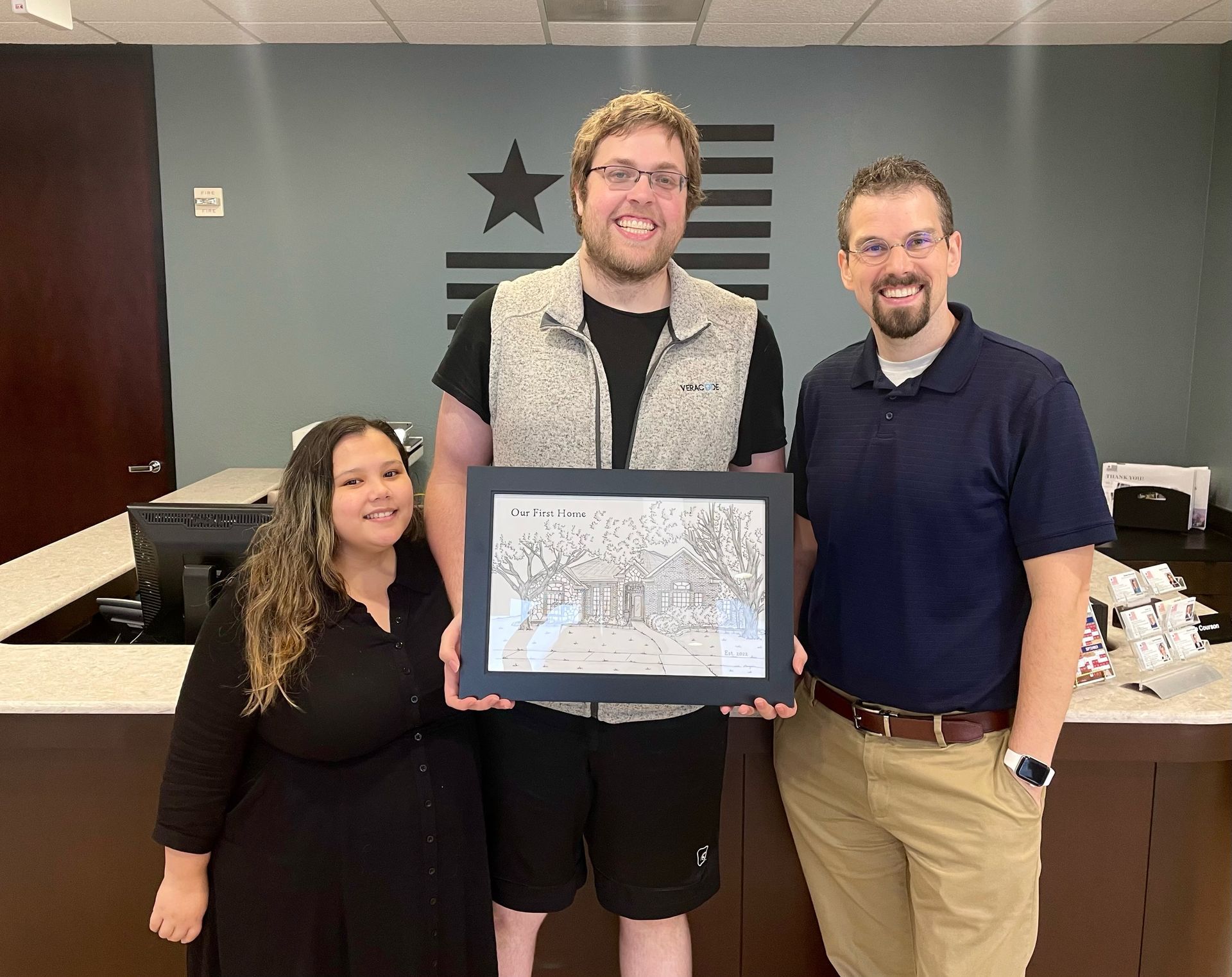 A man and a woman are taking a selfie in front of their new home.