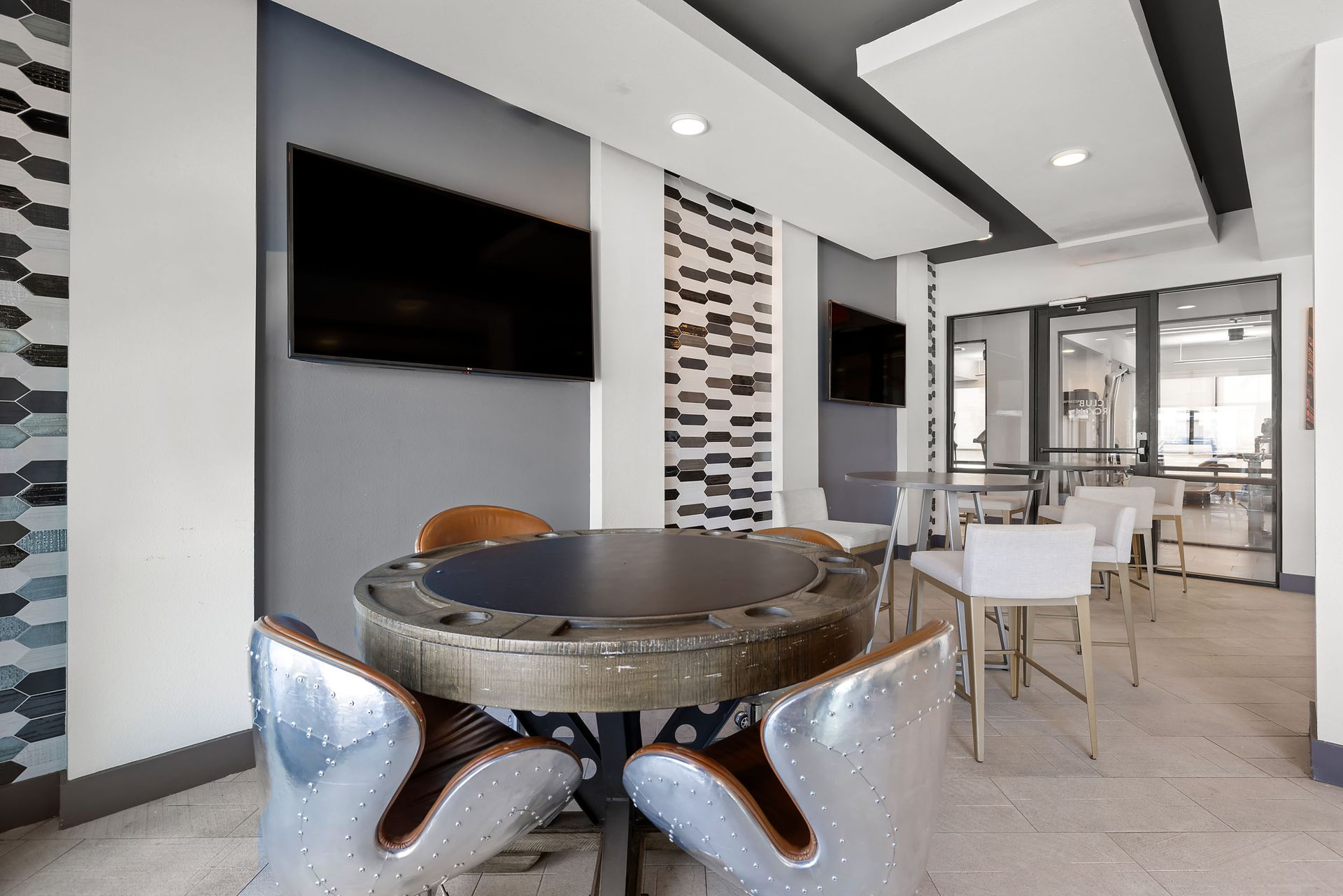 Student apartment clubhouse with a table and chairs and a television on the wall at The Heights offers student apartments for rent near SHSU in Huntsville, TX.