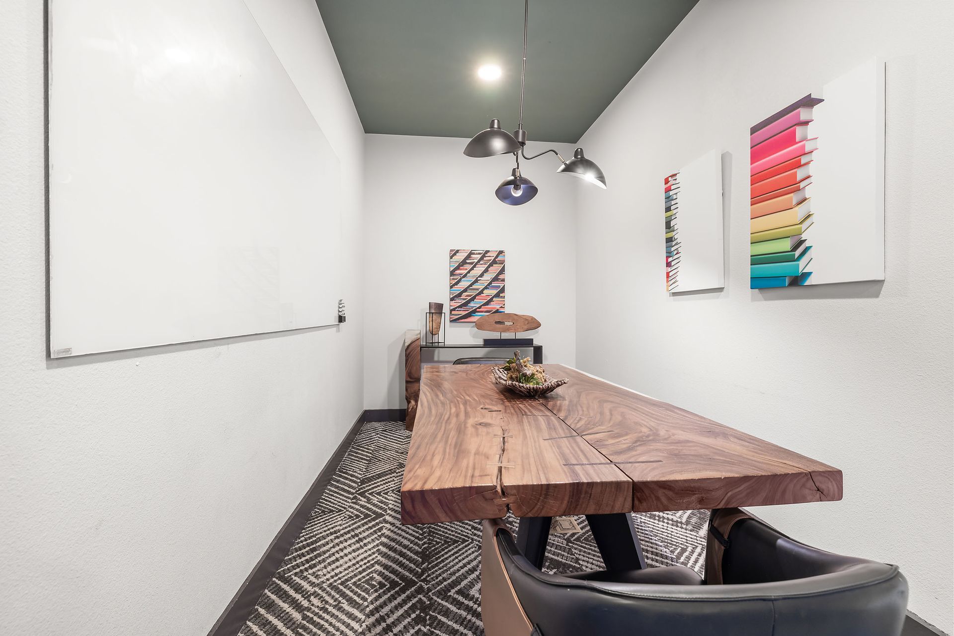 Apartment community study room with a whiteboard, wall painting, long wooden table, and chairs at The Heights offers student apartments for rent near SHSU in Huntsville, TX.