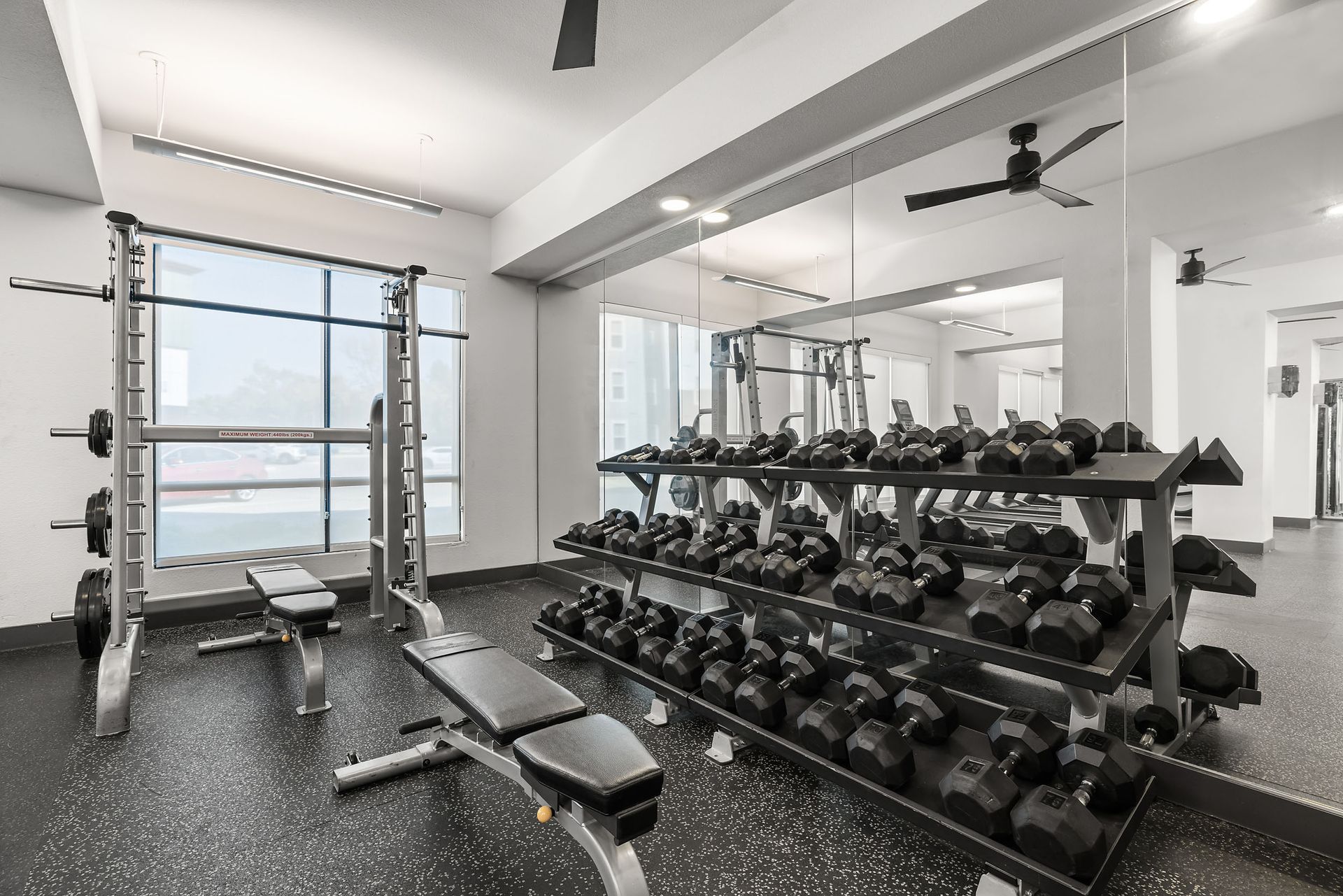 A gym with a lot of dumbbells and a bench at The Heights offers student apartments in Huntsville, TX.