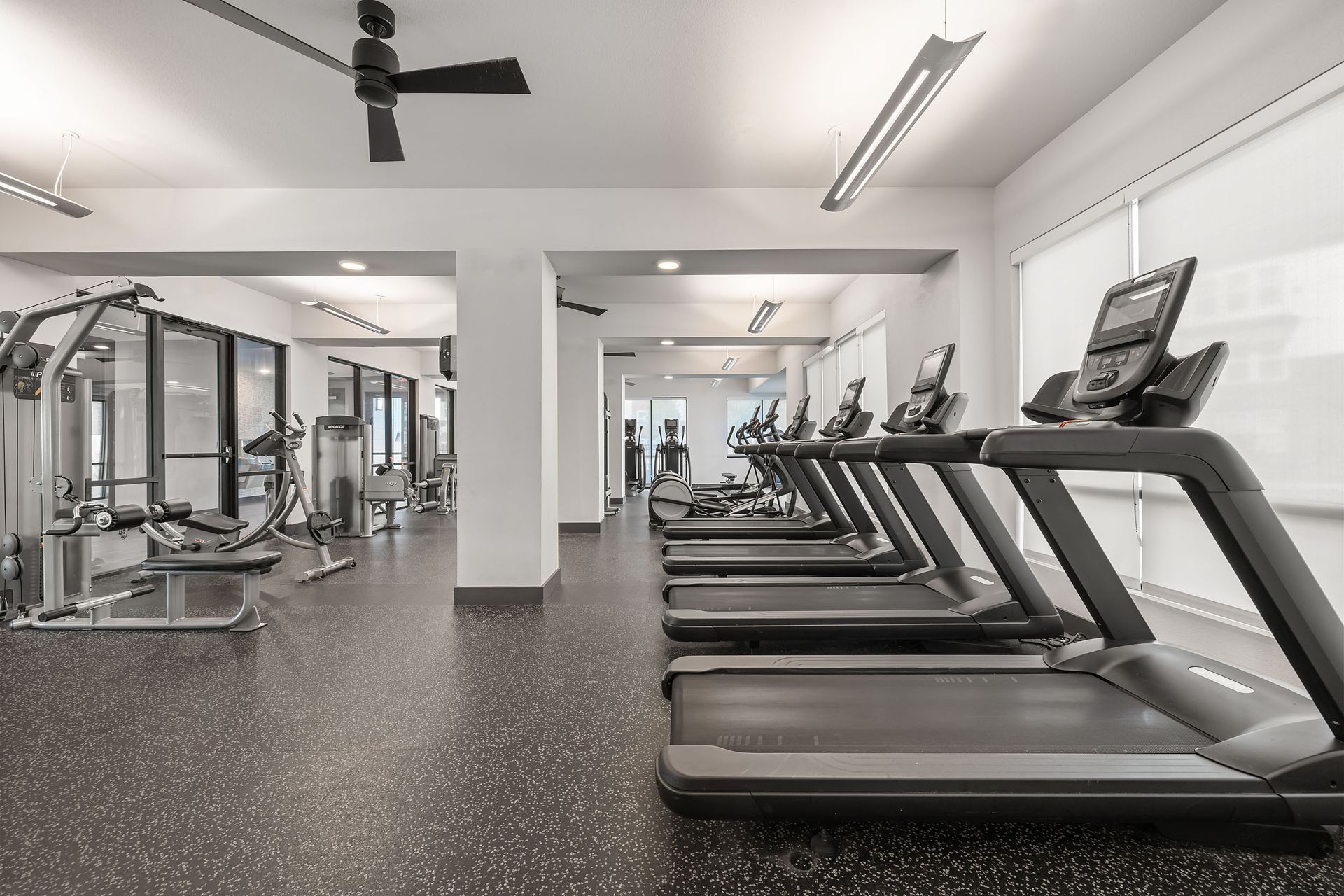 A gym with a lot of treadmills and a ceiling fan at The Heights offers student apartments near SHSU in Huntsville, TX.