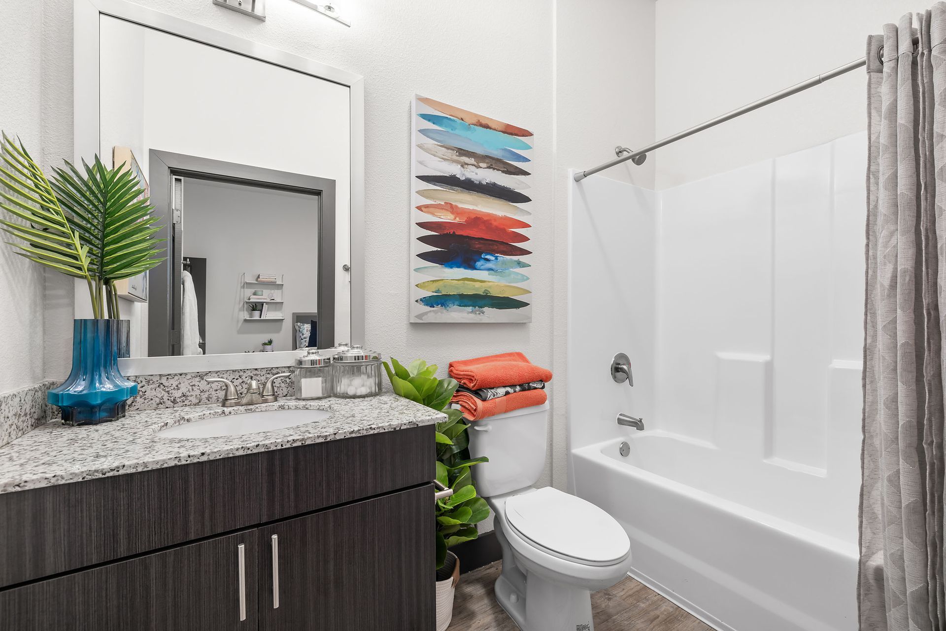 A bathroom with a sink, toilet, bathtub and mirror at The Heights offers apartments for rent near SHSU in Huntsville, TX.