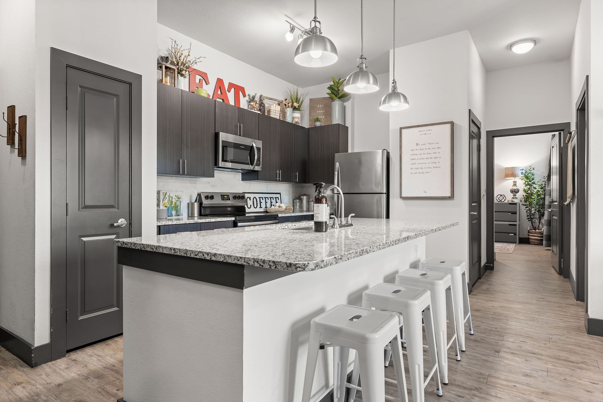 Apartment modern kitchen with a large island, stools, and a refrigerator at The Heights offers student apartments for rent near SHSU in Huntsville, TX.