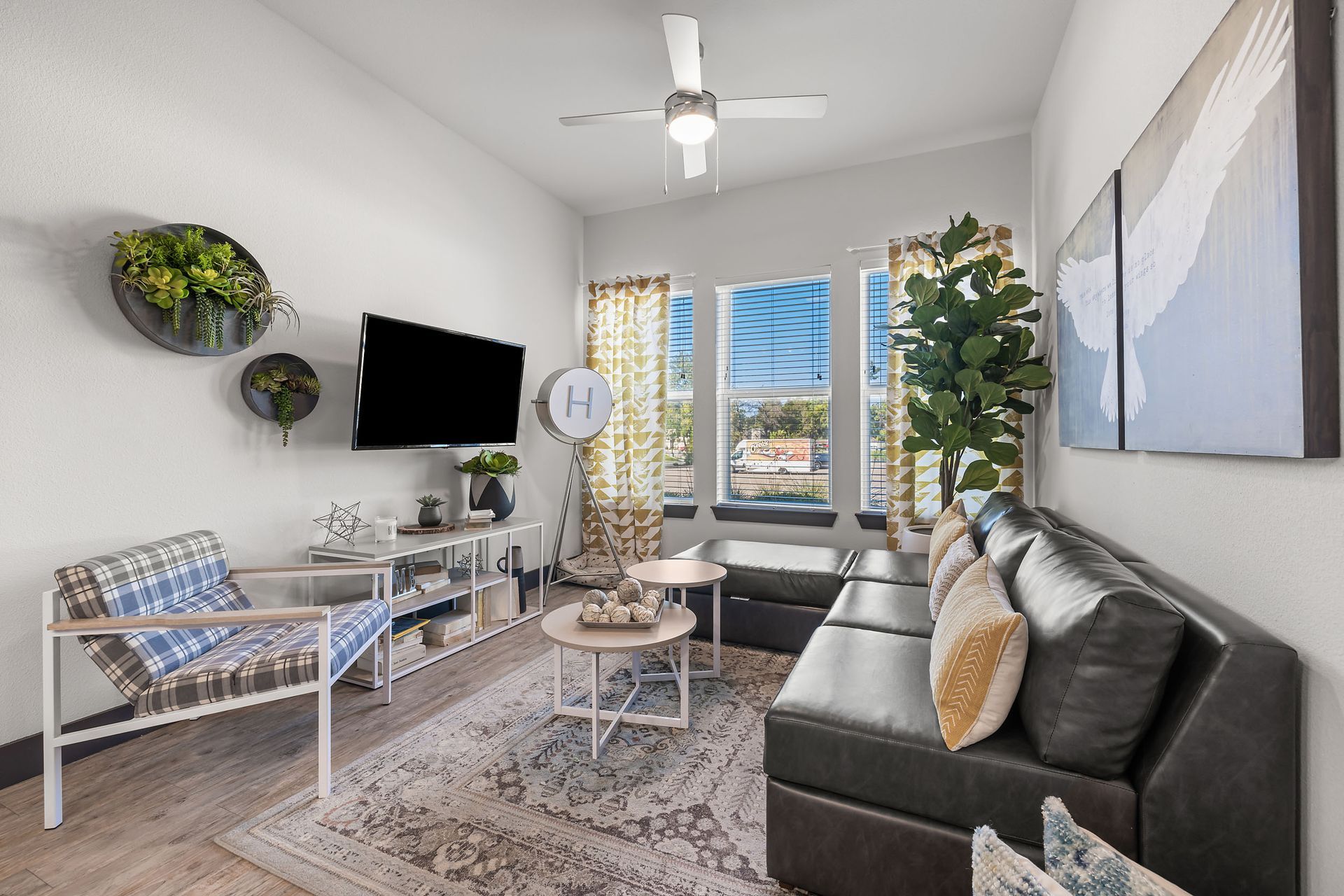 Apartment living room with a couch, chairs, a television, and a ceiling fan at The Heights offers student apartments for rent near SHSU in Huntsville, TX.