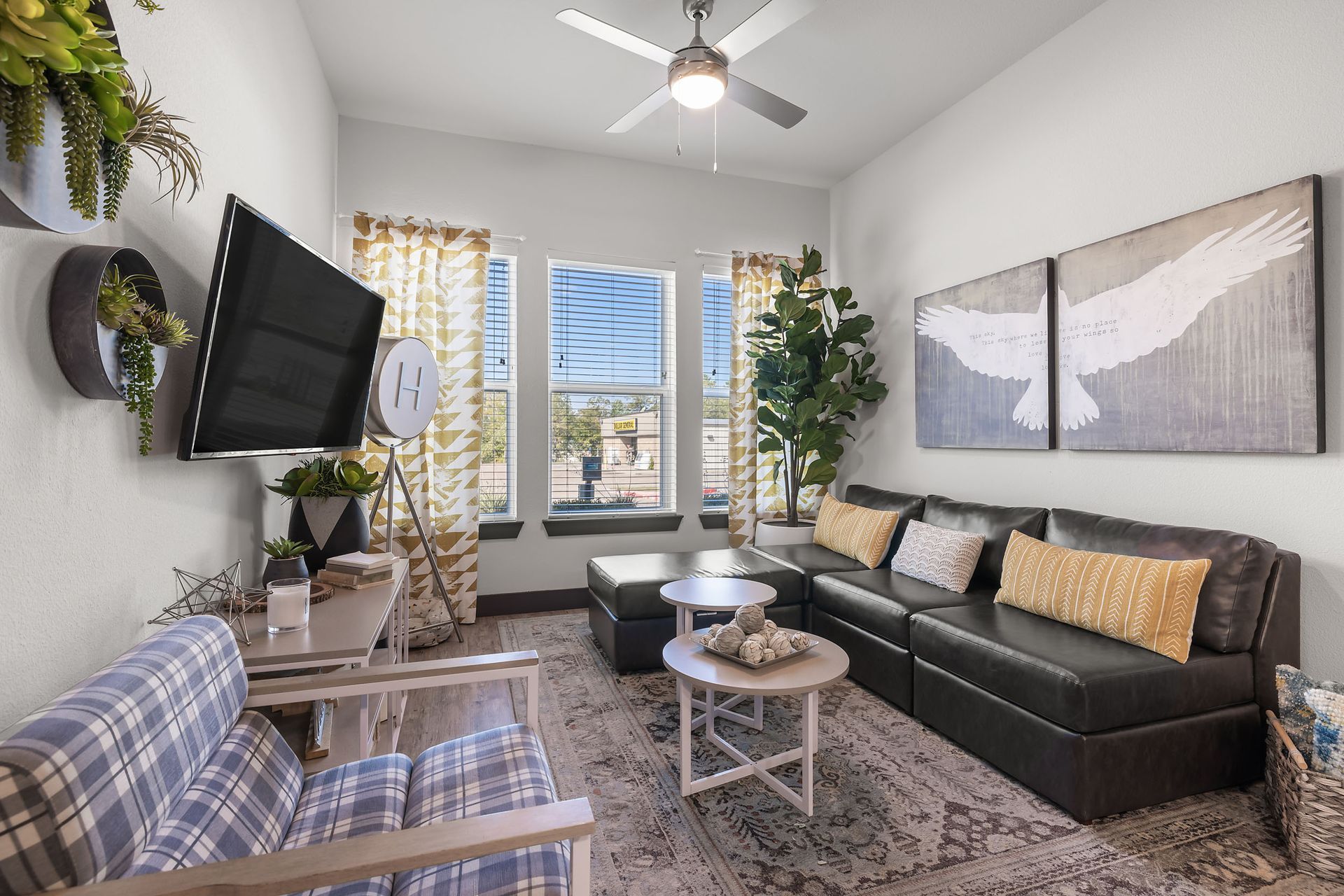 Student apartment living room with a couch, chairs, tables, and a flat screen TV at The Heights offers student apartments for rent near SHSU in Huntsville, TX.