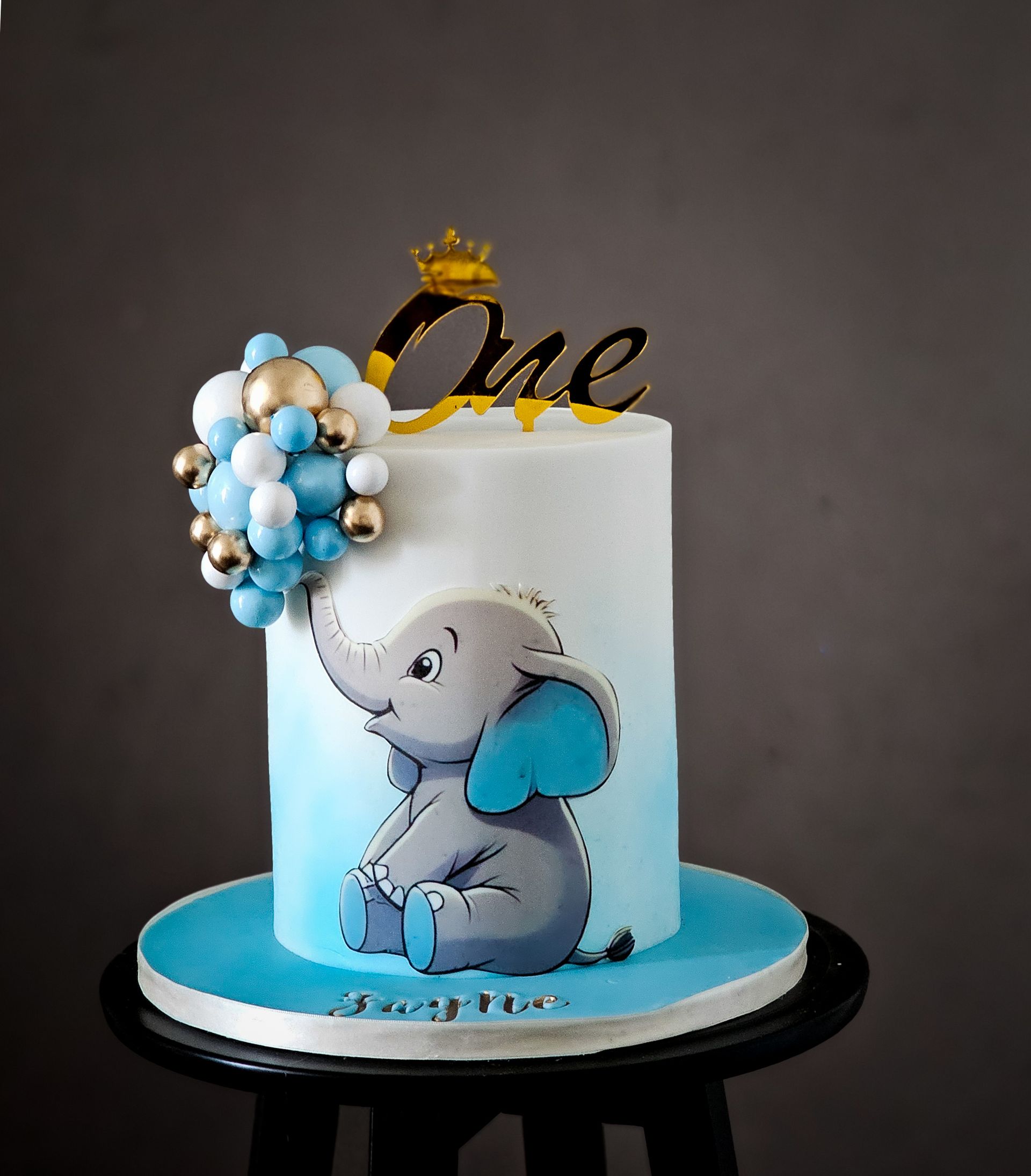 A blue and white cake decorated with a cartoon elephant and 