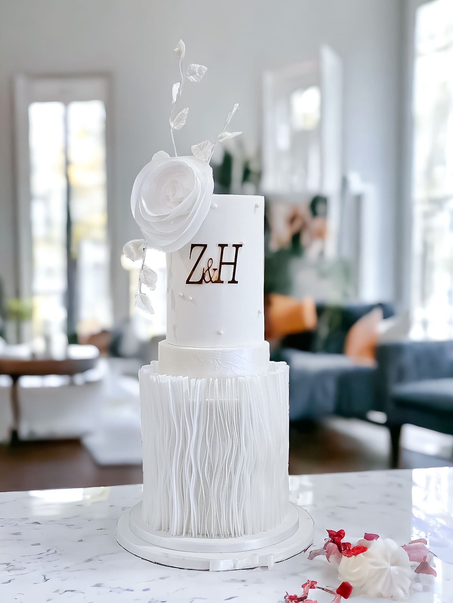 White wedding cake with a textured base and rose topper, initials 
