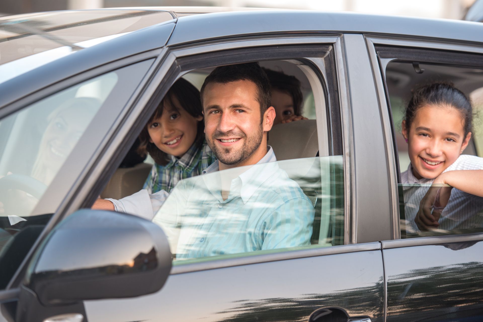 A man and two children are sitting in a car.