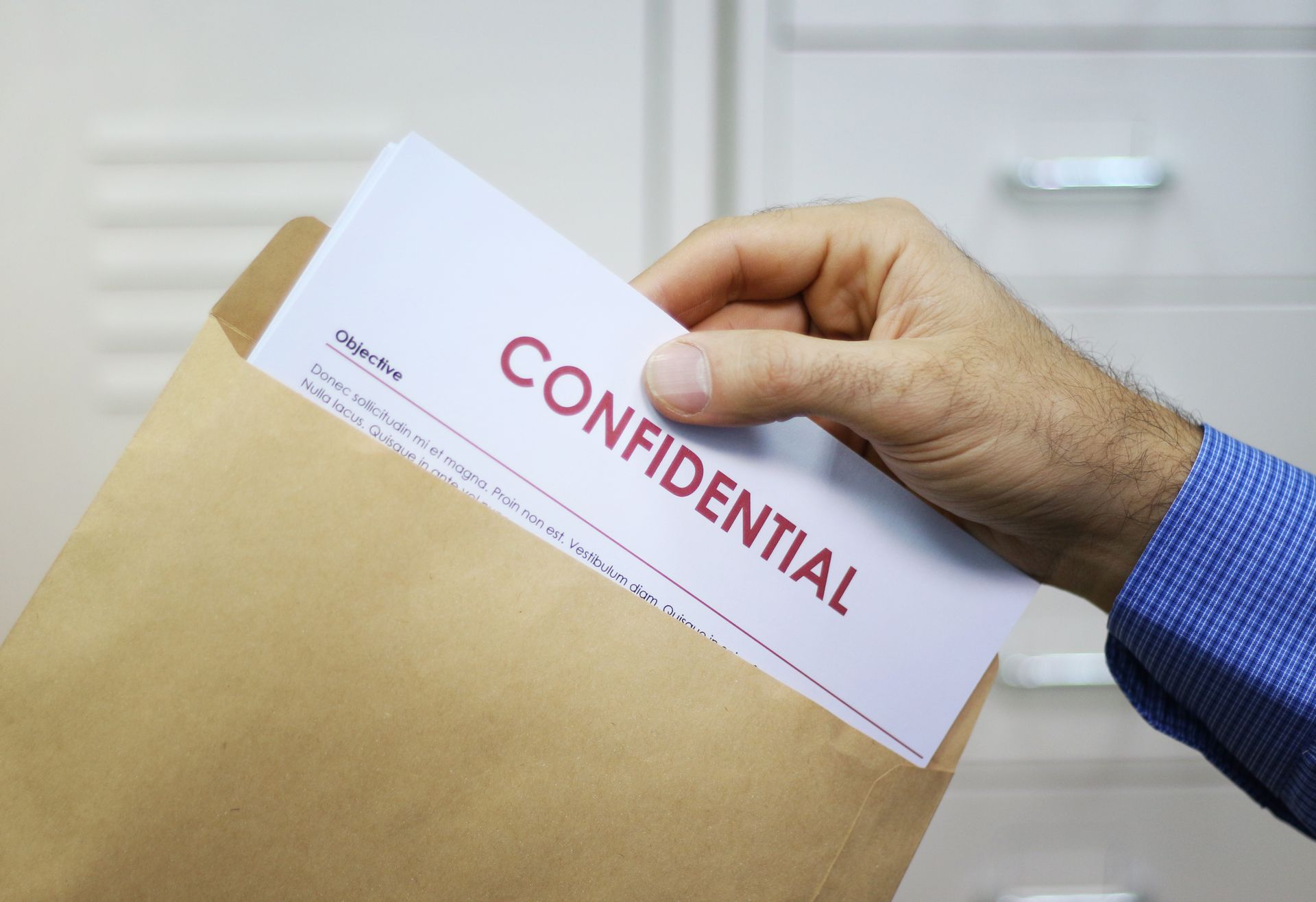 A person is holding a confidential envelope in their hand.