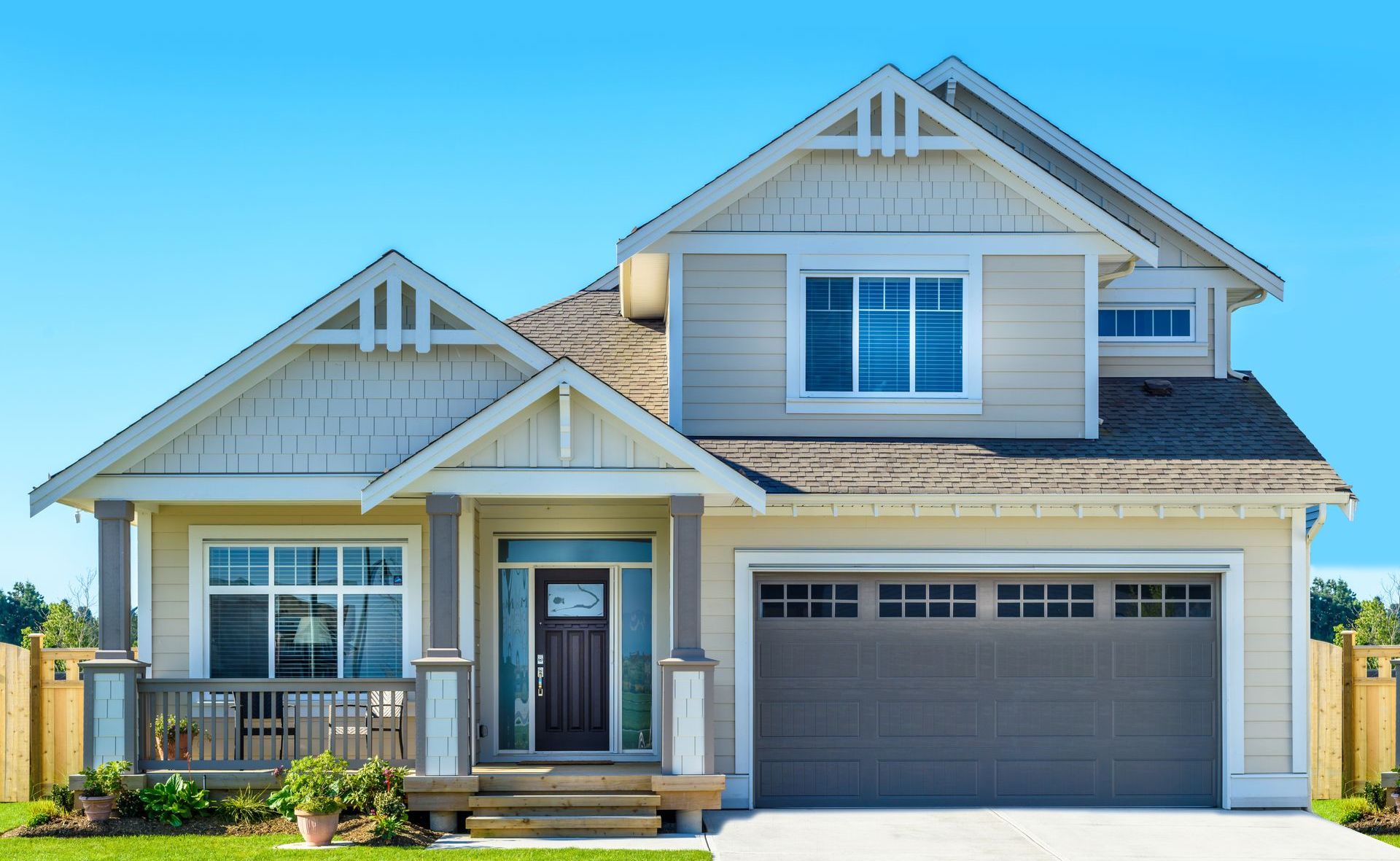A large house with a brown garage door and a blue sky in the background.