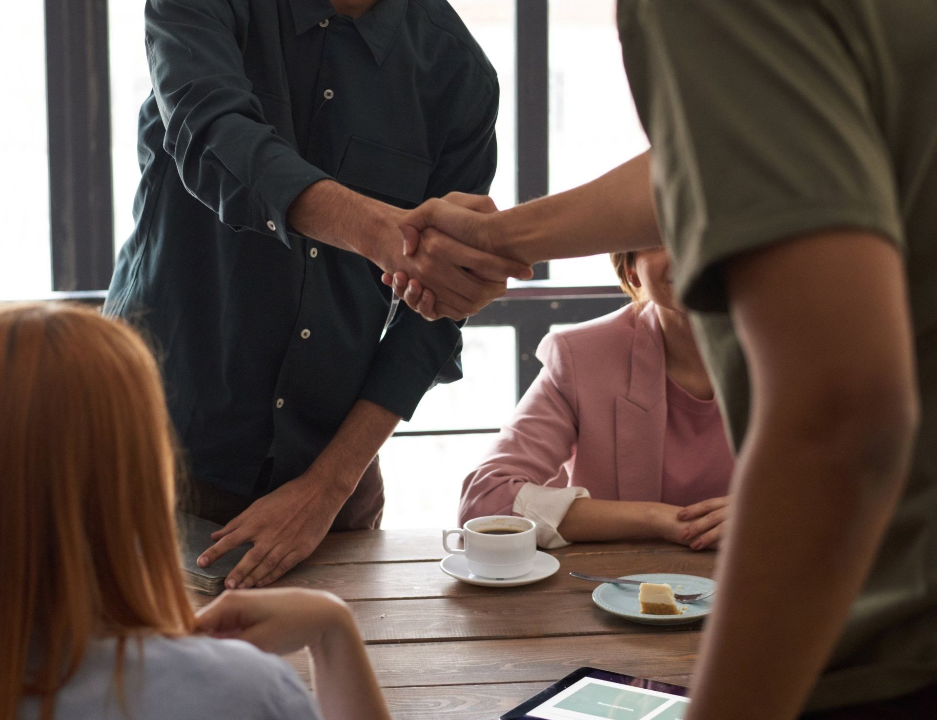 A group of people are shaking hands while sitting at a table.