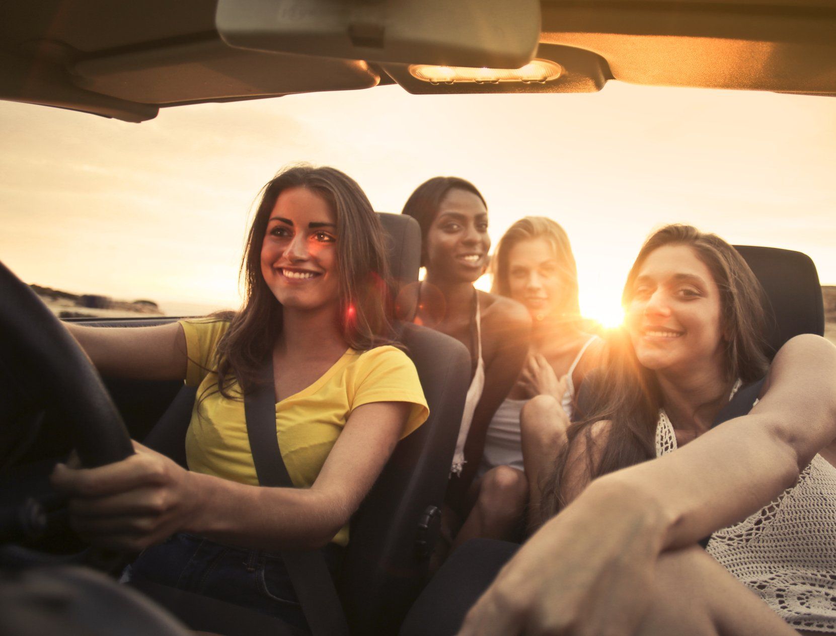 A group of young women are sitting in the back seat of a car.