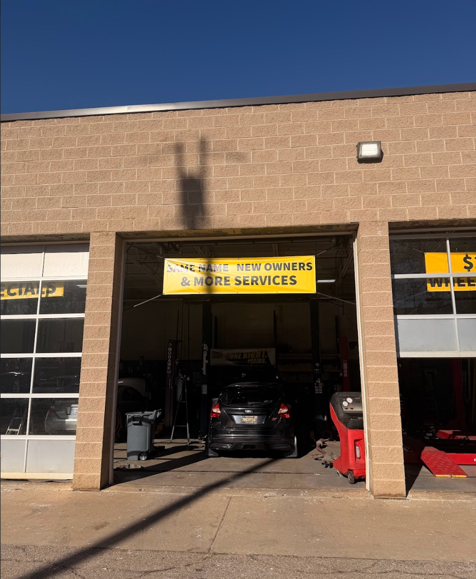 Exterior view of auto repair shop with garage bays open. A car is inside one bay, under a sign.