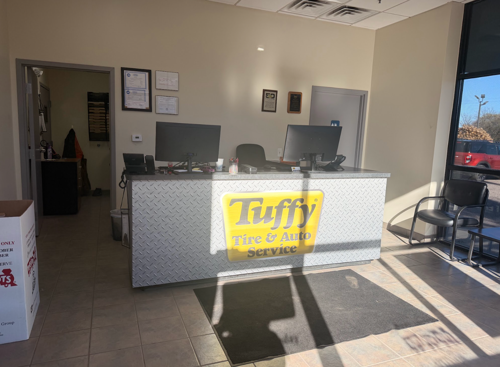 Interior of a Tuffy Tire & Auto Service reception area with a counter, computers, and a door to the service area.