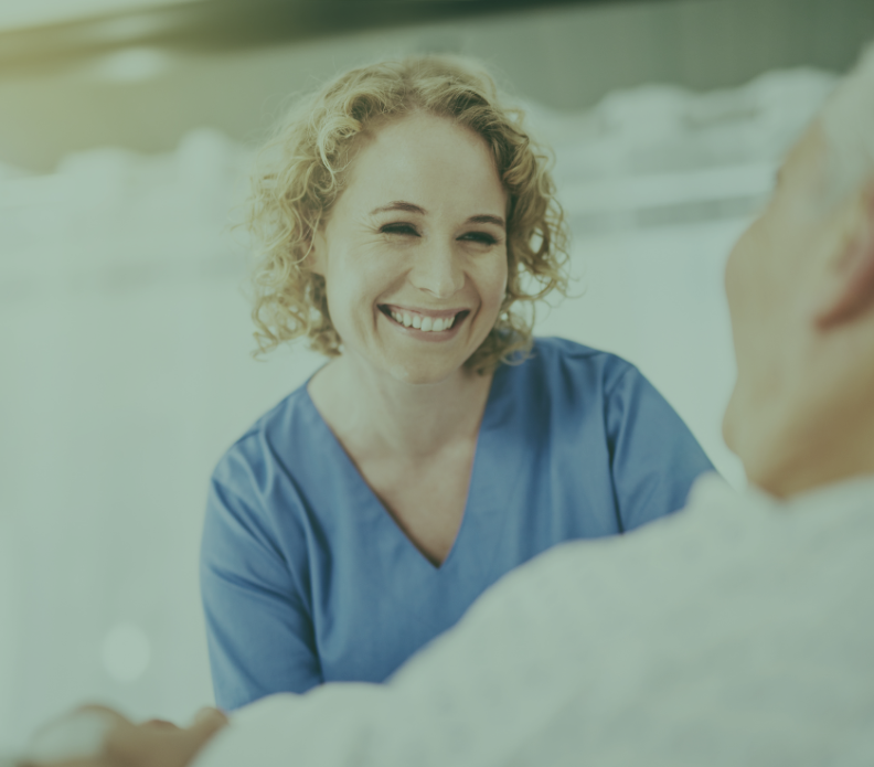 A nurse is smiling while talking to an elderly man.
