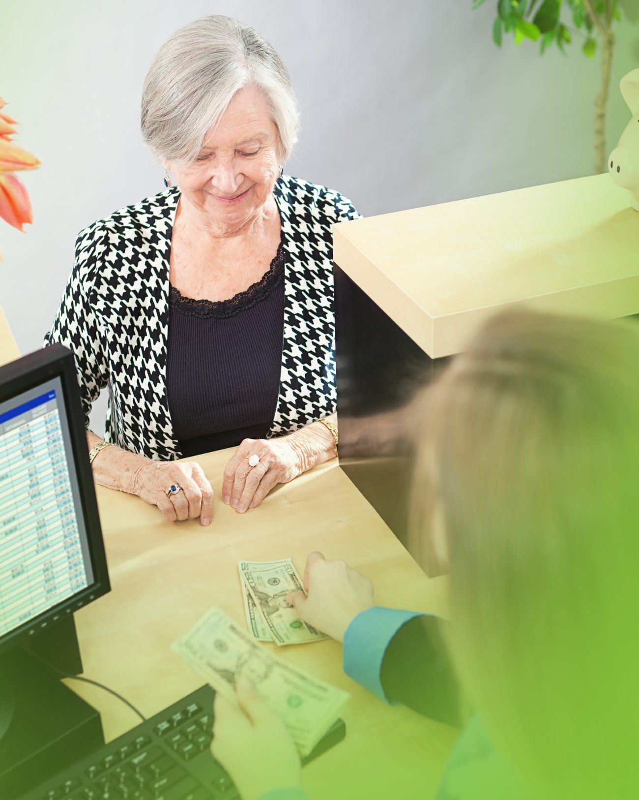 A woman is sitting at a desk in front of a computer counting money.