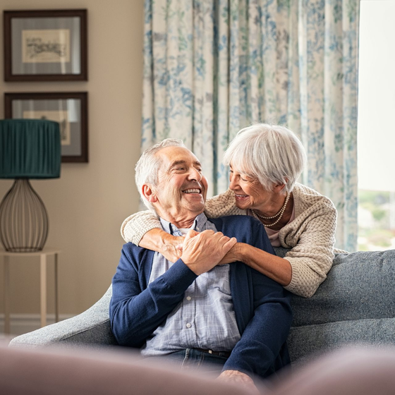An elderly man is sitting on a couch with his family.
