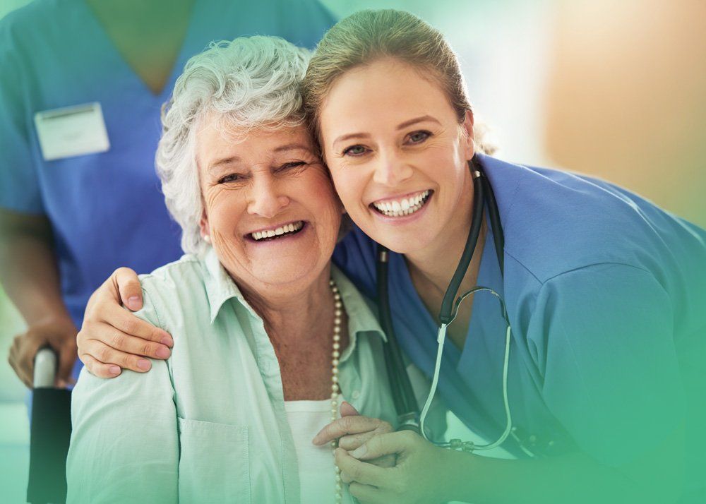 A nurse is hugging an elderly woman in a wheelchair.