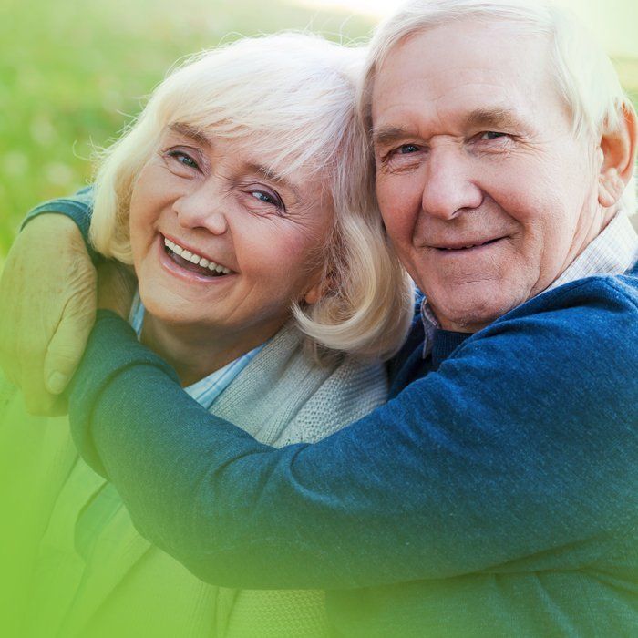 A man and a woman are hugging each other and smiling.