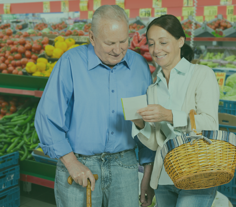A woman is helping an elderly man with a cane in a grocery store.