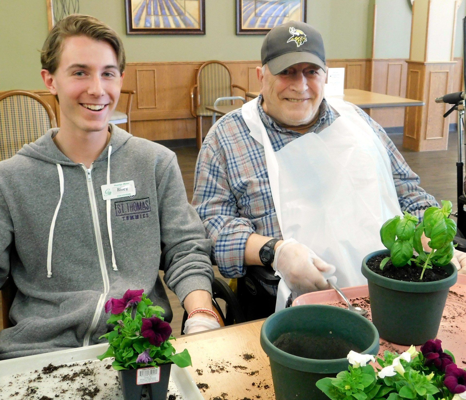 A man and a boy are sitting at a table with potted plants
