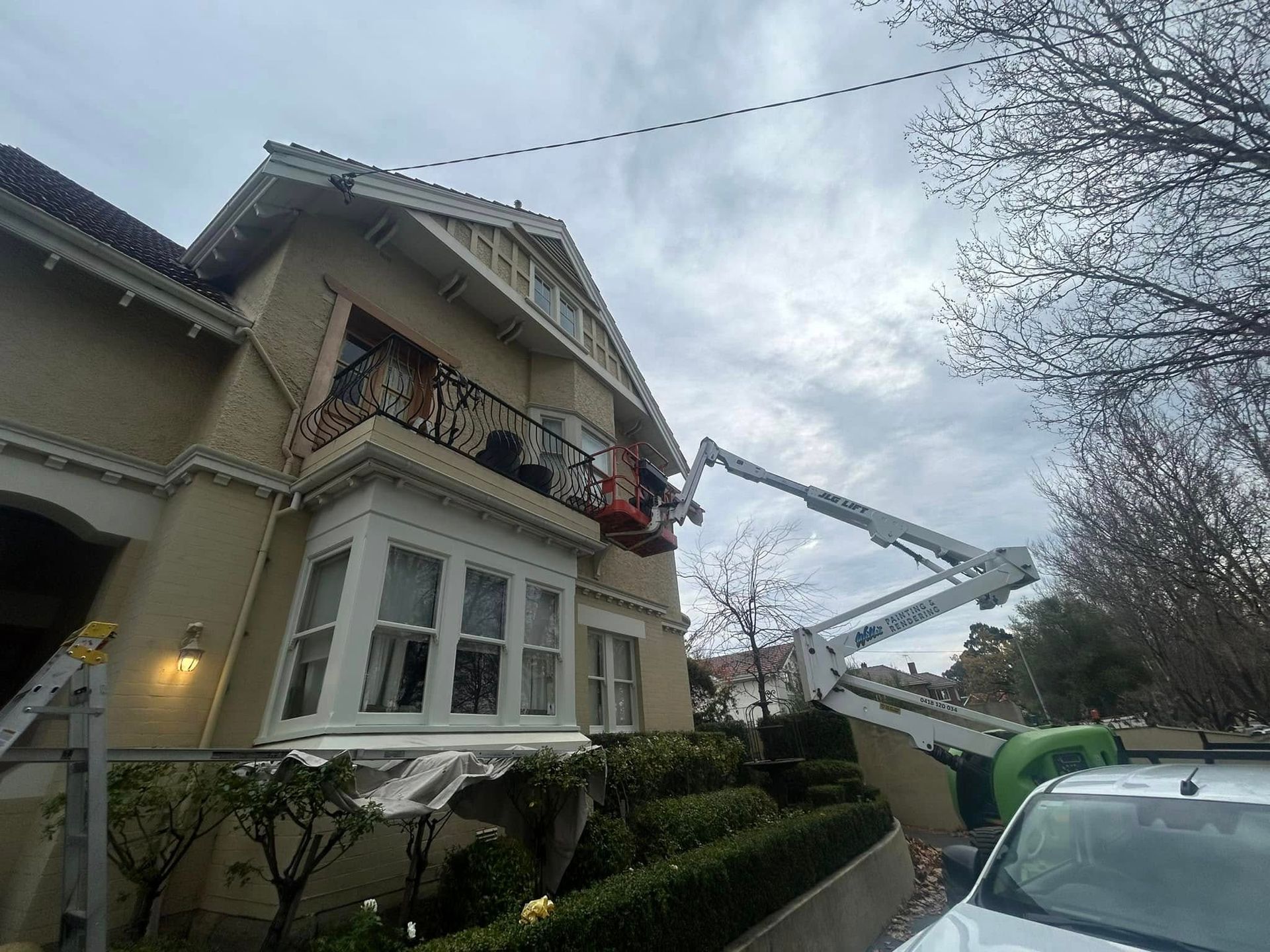 A large house is being painted by a crane.