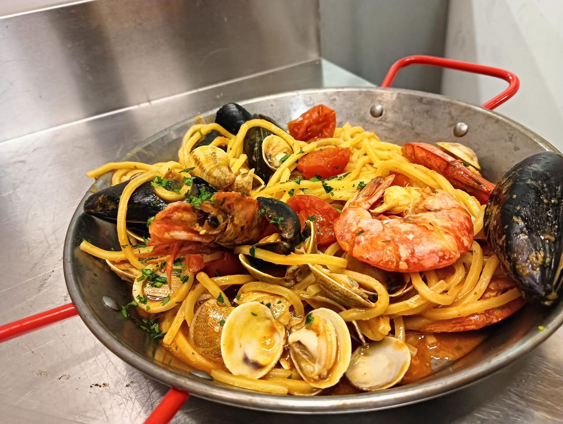 Paella di pesce in una padella capiente con gamberi, cozze, vongole e fette di limone.