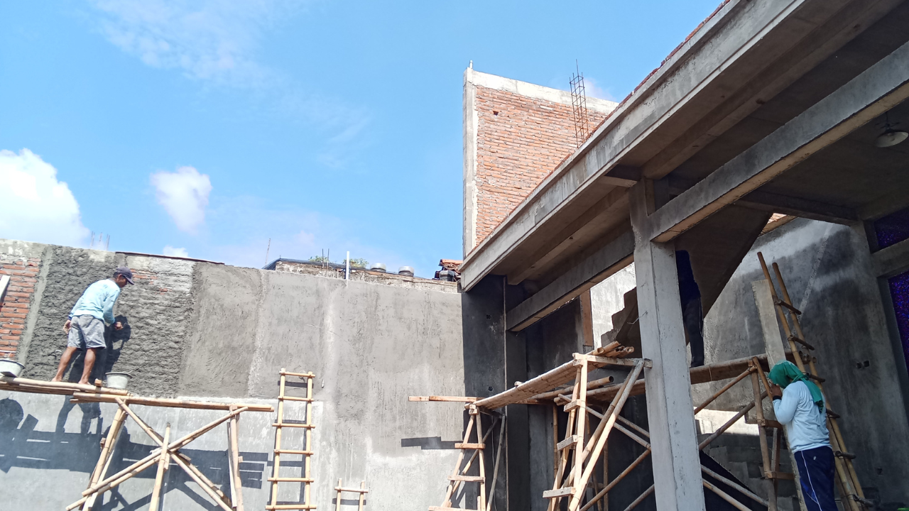 Construction workers plastering a building's exterior. Scaffolding, gray walls, blue sky.
