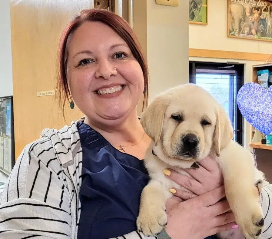 A woman is holding a puppy in her arms and smiling