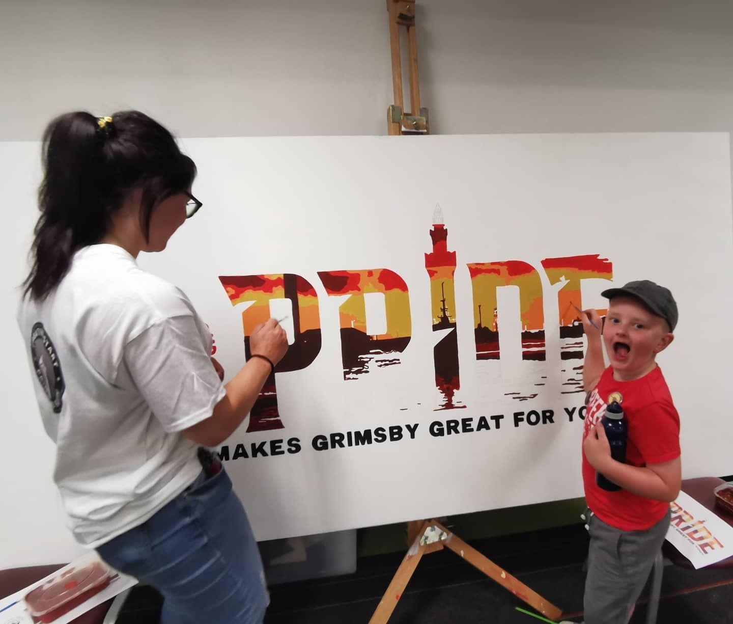 A woman paints a sign that says 