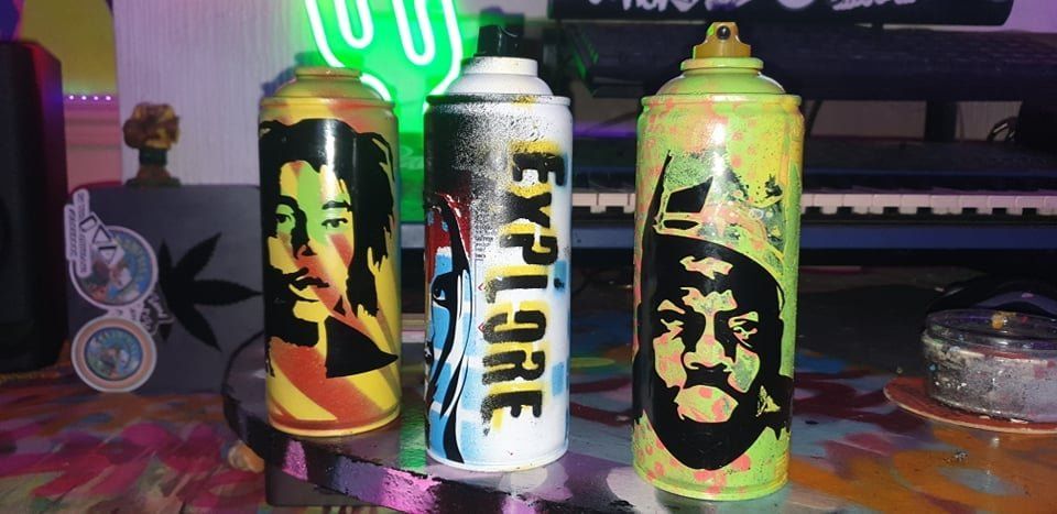 Three cans of spray paint are sitting on a table.