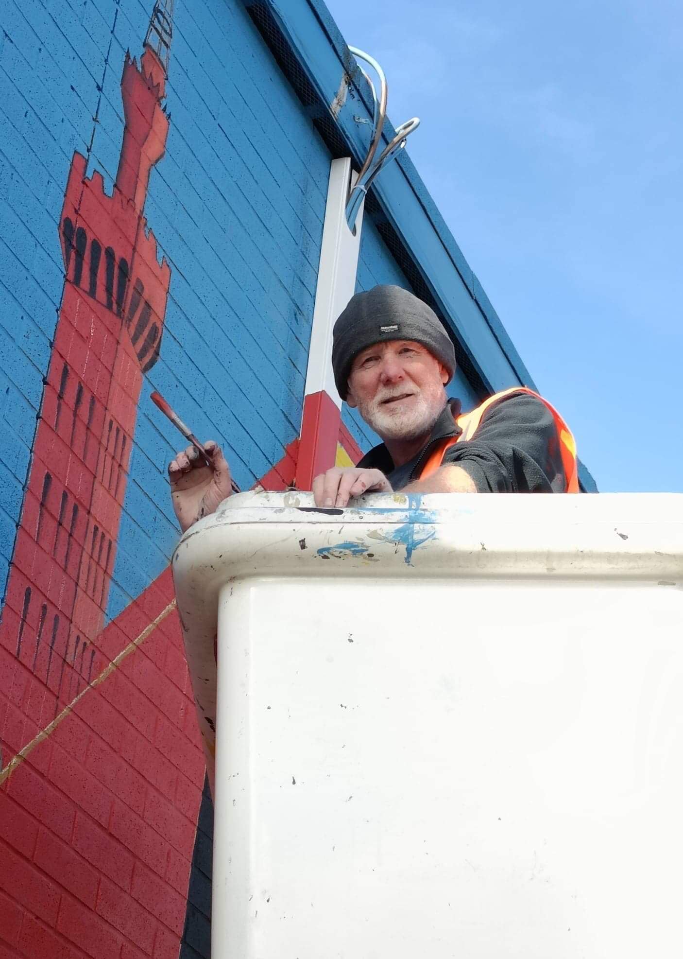 A man paints a mural on the side of a building