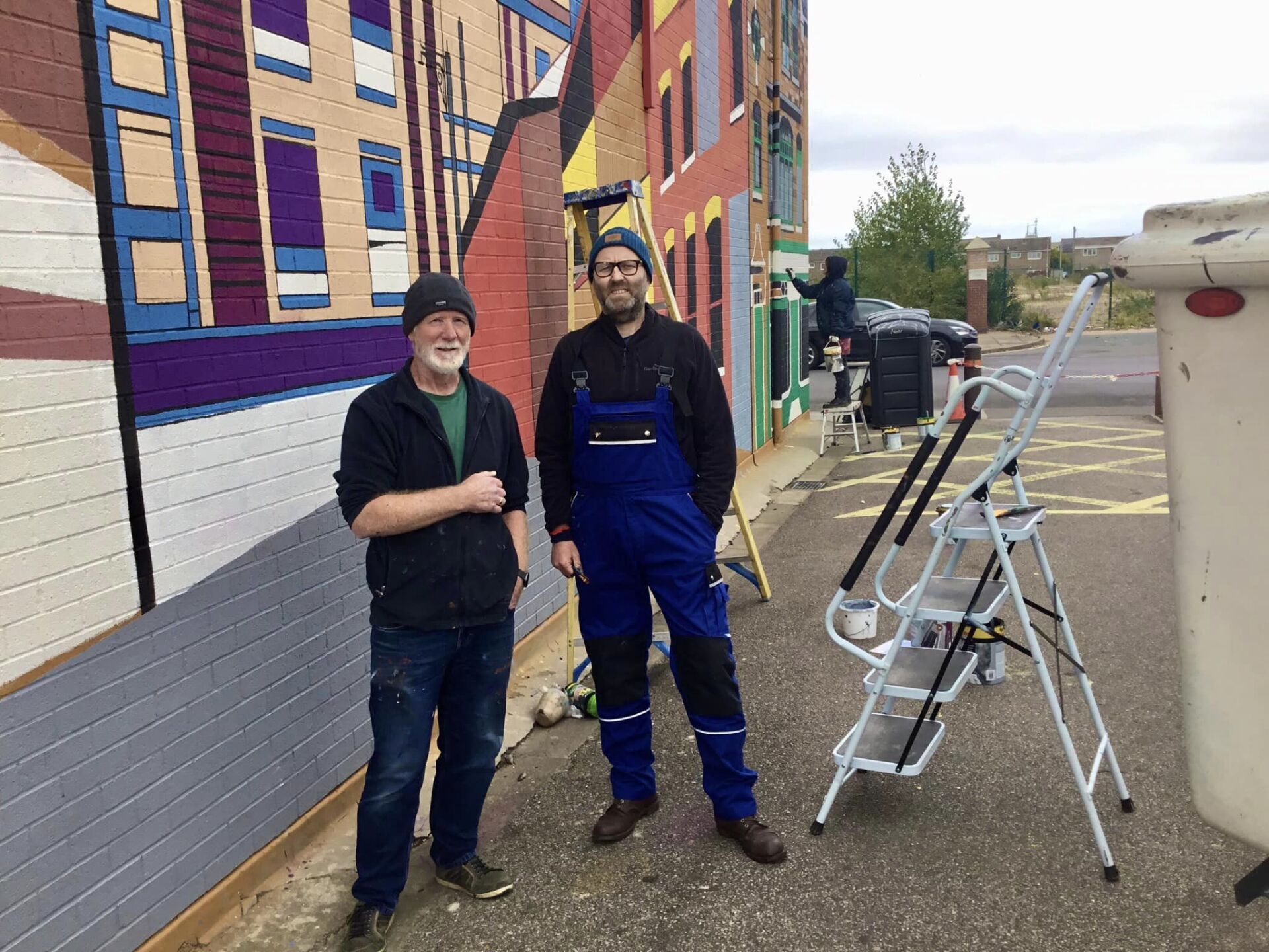 Two men are standing next to each other in front of a building.