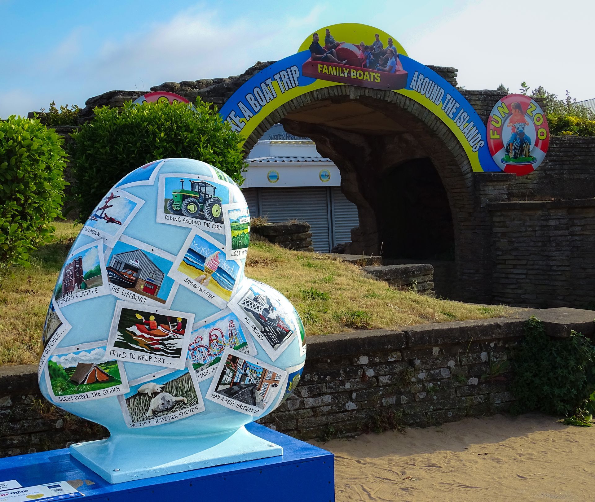 A statue of a heart with pictures on it sits in front of a sign that says