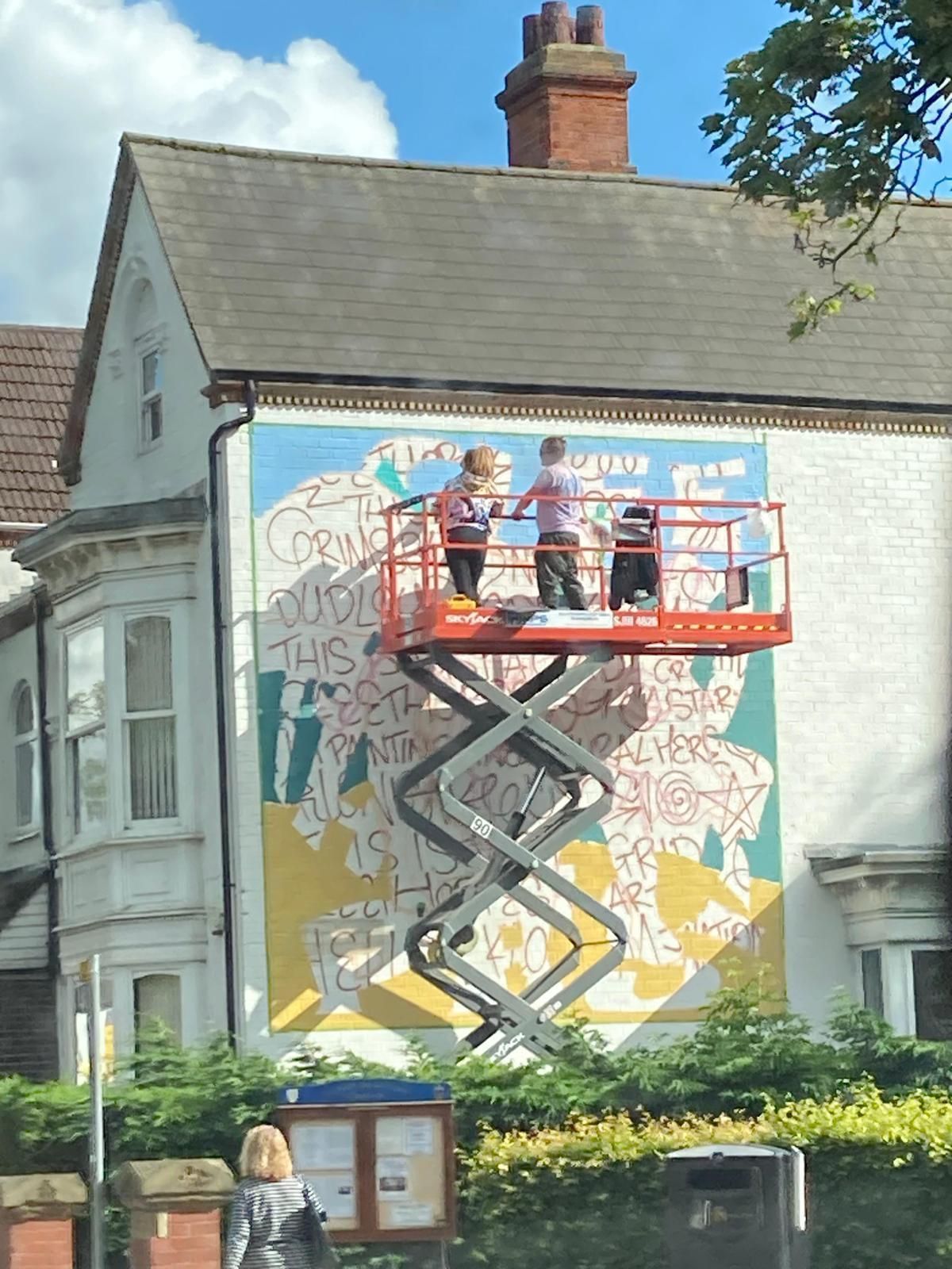 A mural is being painted on the side of a building