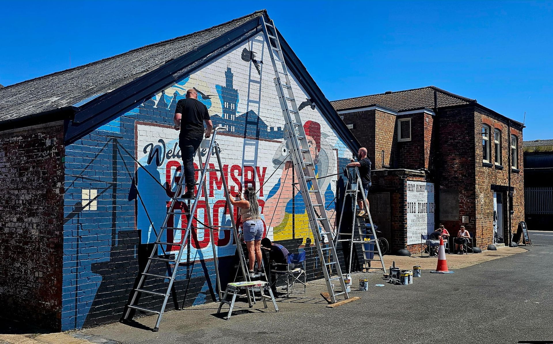 A group of people are painting a mural on the side of a building.