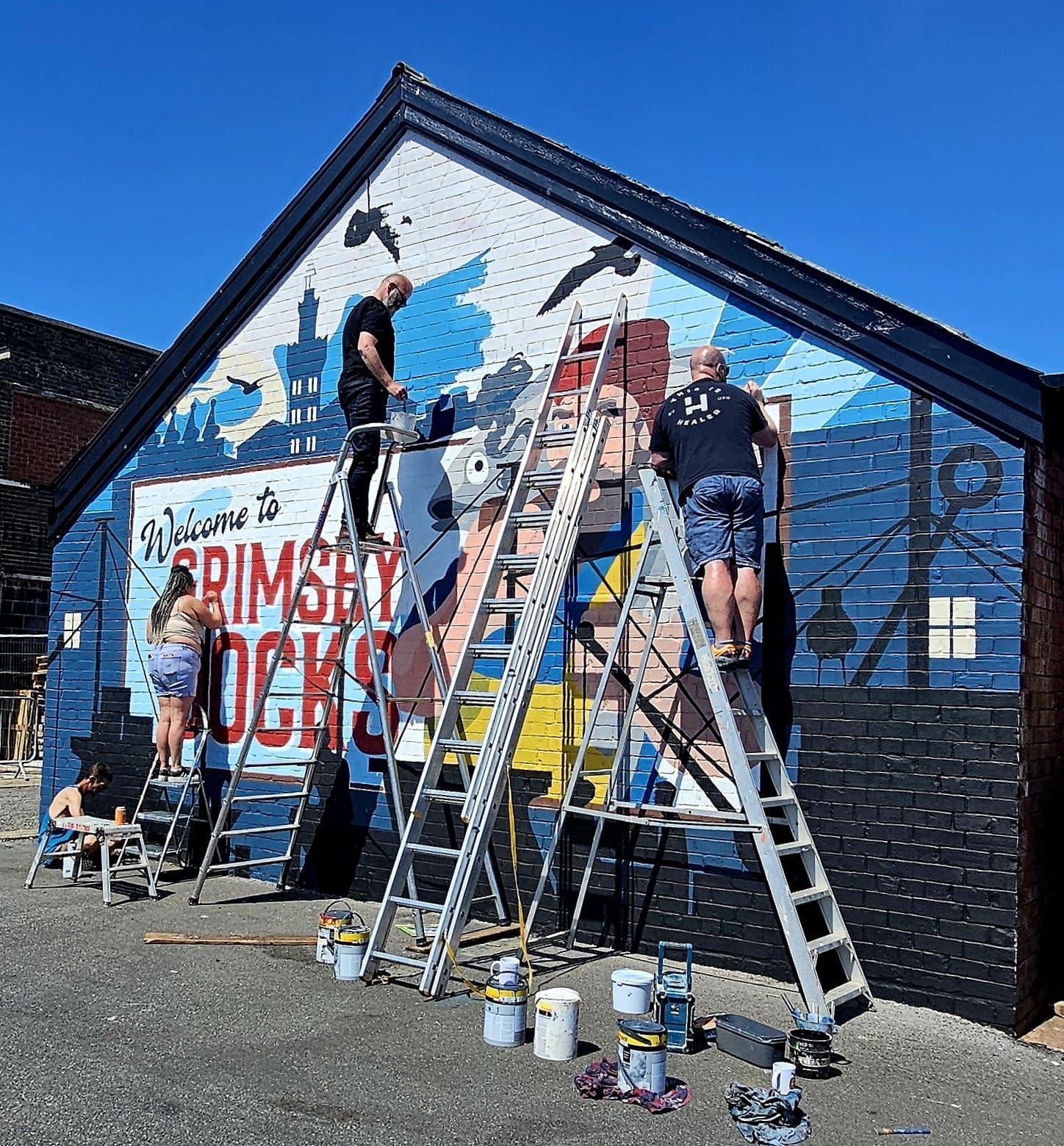 A group of people are painting a mural on the side of a building.