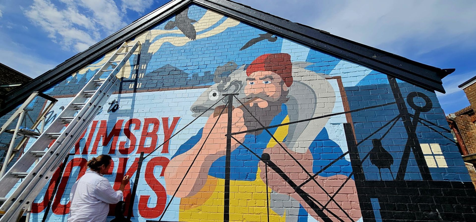 A man is painting a mural on the side of a building.