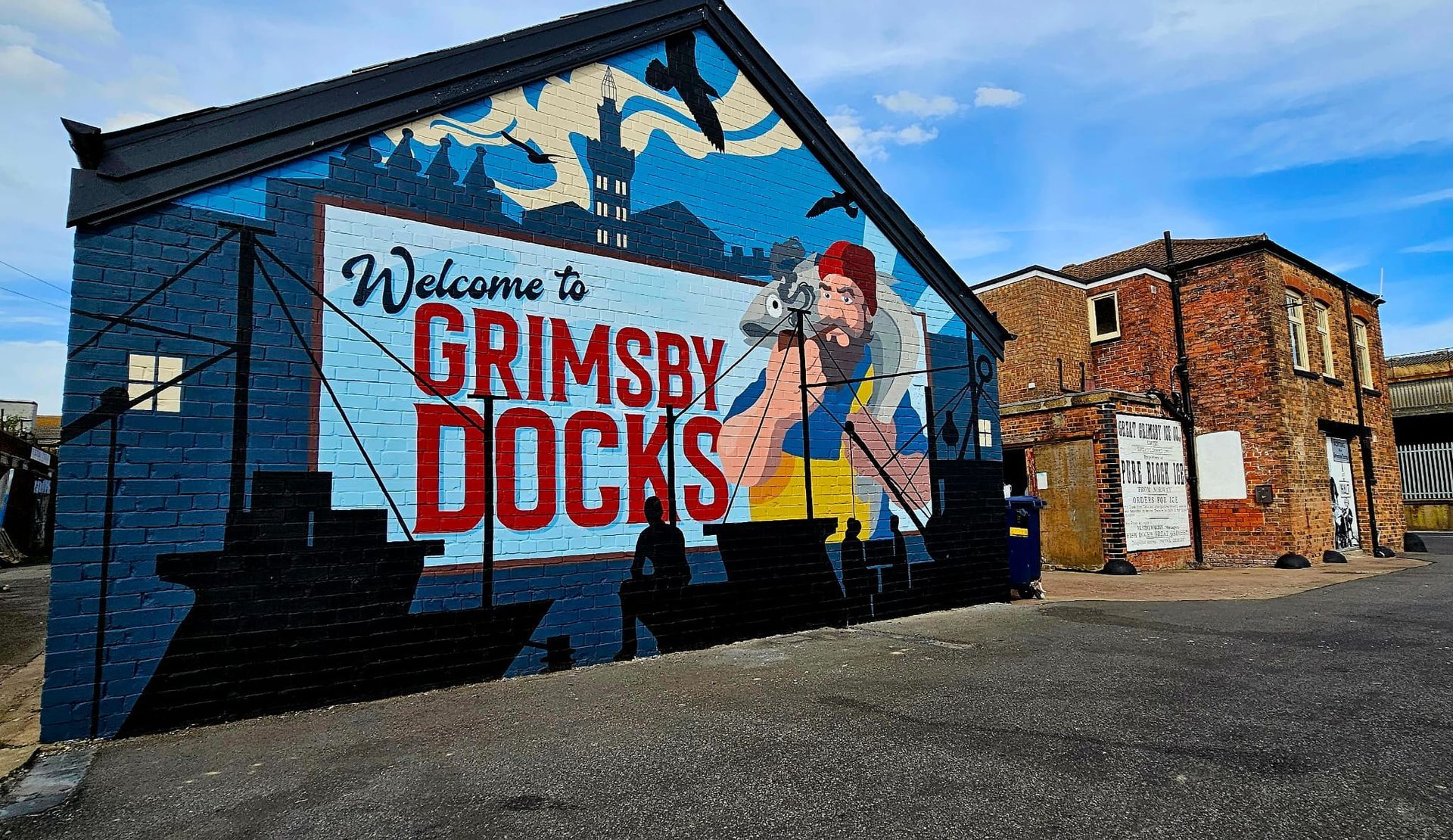 A mural on the side of a building that says welcome to grimsby docks