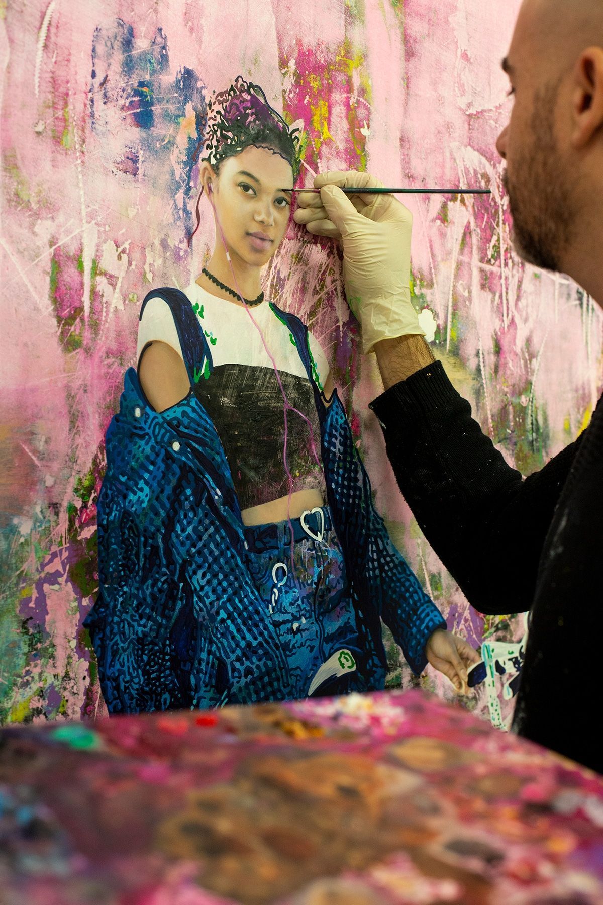 A man is painting a picture of a woman in a blue jacket.
